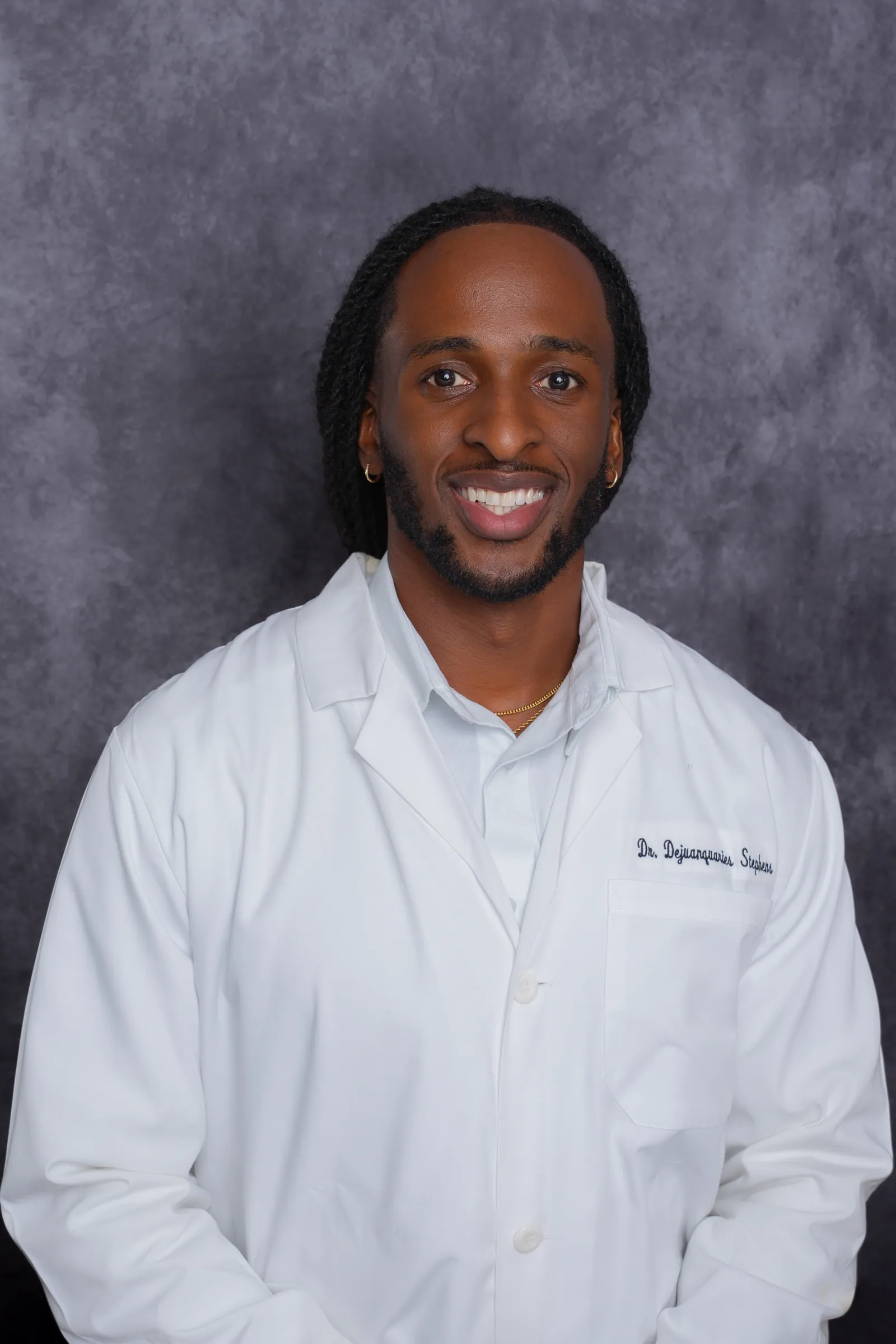 Professional headshot of a man in a white coat, seated pose